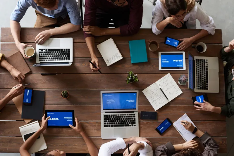 Overhead view of a team reviewing documents and charts around a wooden meeting table.